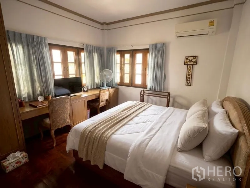 独栋房屋 for sale in Suan Luang, Bangkok - 明亮卧室，双人床、内置书桌、窗户与空调。