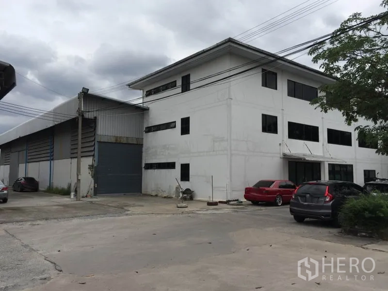 货栈 出租在Saphan Sung, Bangkok - 外观图：仓库连三层办公楼，设卷闸装卸门与地面停车位。