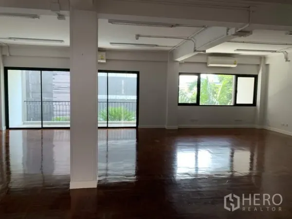 Office Space for rent in Watthana, Bangkok - Bright open-plan office with polished wood floors, sliding glass doors to a balcony, and large windows.