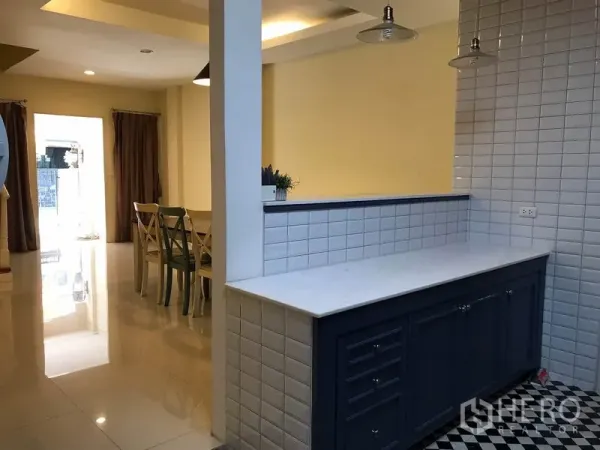Townhouse for rent in Wang Thonglang, Bangkok - Breakfast bar with marble counter and white tiles looking toward the dining area and front patio light.