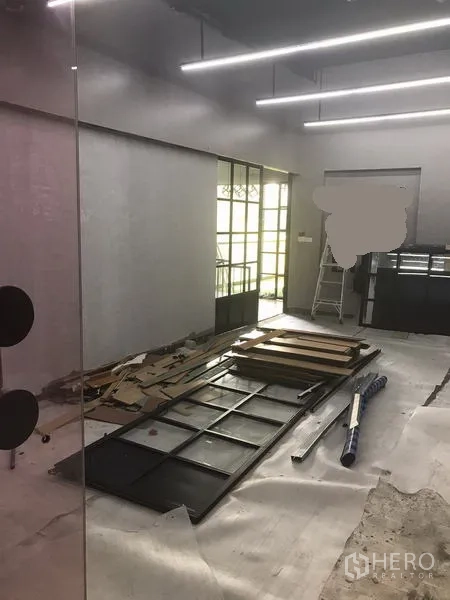 零售空间 出租在Watthana, Bangkok - 开放式零售空间，玻璃隔断与金属框门，地面摆放装修材料