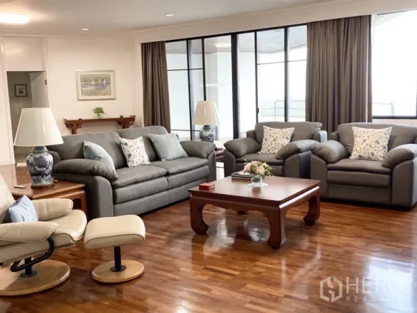 Condominium for rent in Yan Nawa, Bangkok - Spacious living room with grey sofas, wood floors and large balcony doors.