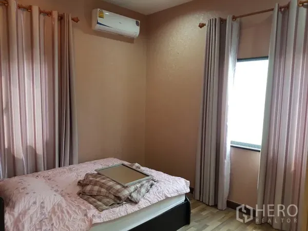 Detached House for sale in Samut Prakan - Cozy bedroom with air conditioner, pastel walls, curtains and a double bed.