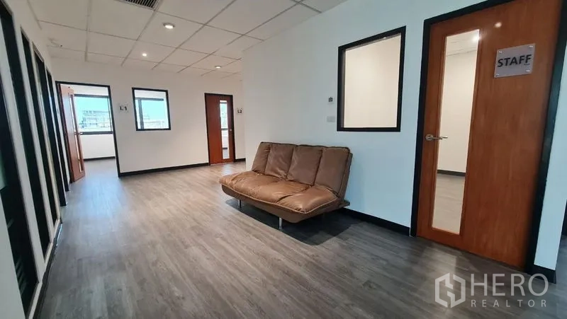 Office Space for rent in Watthana, Bangkok - Lounge area in the corridor with a sofa, staff room door and downlights.