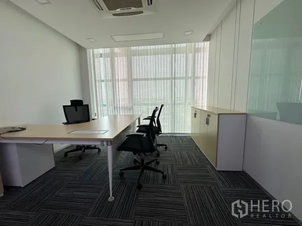 Office Space for rent - Executive office setup with desk and visitor chairs facing floor-to-ceiling windows with sheer blinds.