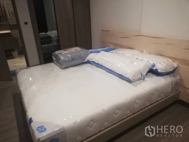 คอนโด ให้เช่าในWatthana, Bangkok - ห้องนอนพร้อมที่นอนใหม่ หัวเตียงไม้โทนอ่อน และตู้เสื้อผ้าบิวท์อิน มีทางเชื่อมไปยังห้องน้ำ