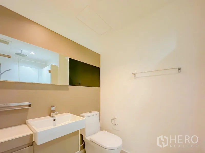 คอนโด ขาย - ห้องน้ำมินิมอล กระจกบานยาว อ่างล้างหน้าเหลี่ยม และโถสุขภัณฑ์โทนอบอุ่น