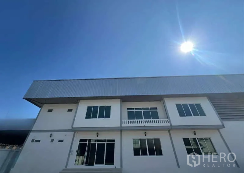 货栈 出租在Prawet, Bangkok - 现代两层仓库外立面，金属屋顶，蓝天晴日。