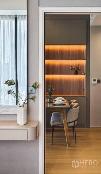 Condominium for rent in Bang Rak, Bangkok - View through doorway to a dining nook with warm backlit shelving and wood flooring.