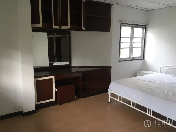 Townhouse for rent in Khlong Toei, Bangkok - Bedroom corner with built-in dressing table, large mirror, and overhead storage.