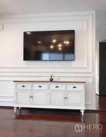 คอนโด ขายในWatthana, Bangkok - ผนังห้องนั่งเล่นตกแต่งบัว กับทีวีจอใหญ่และตู้คอนโซลสีขาว