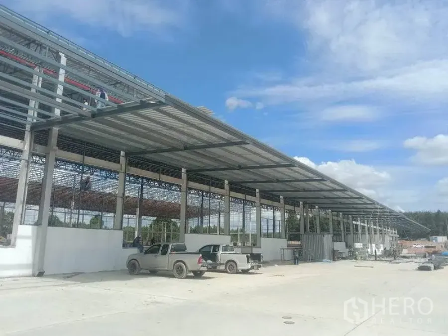 คลังสินค้า ให้เช่าในPluak Daeng, Rayong - มุมมองภายนอกโกดังโครงสร้างเหล็กใหม่ ชายคาขนถ่ายยาวและลานคอนกรีตกว้าง มีรถกระบะจอด