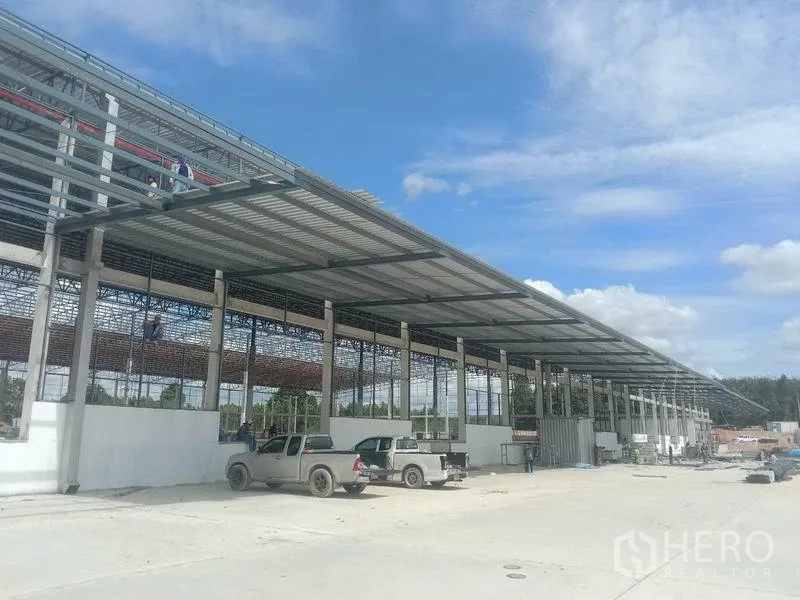 คลังสินค้า ให้เช่าในPluak Daeng, Rayong - มุมมองภายนอกโกดังโครงสร้างเหล็กใหม่ ชายคาขนถ่ายยาวและลานคอนกรีตกว้าง มีรถกระบะจอด