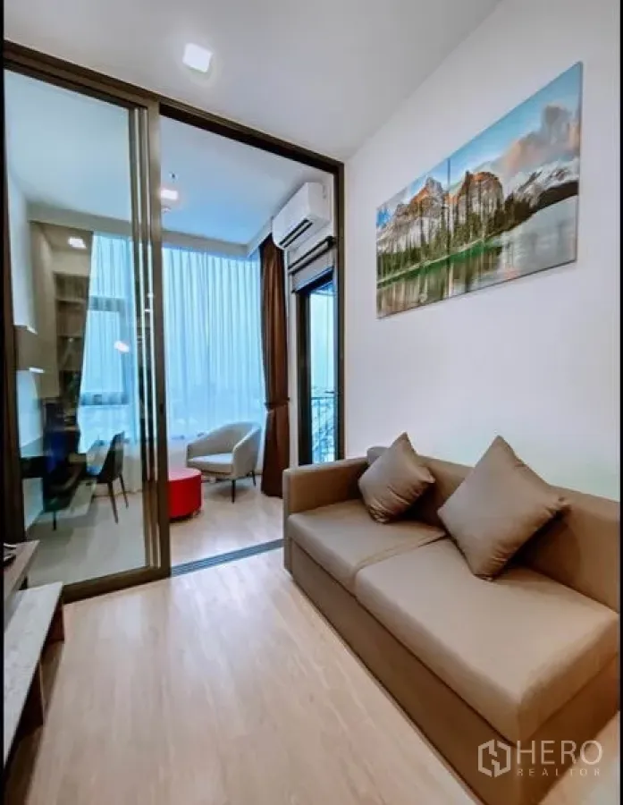 Condominium for sale in Huai Khwang, Bangkok - Bright living room with sofa, sliding glass door and corner window study area in a Huai Khwang, Bangkok condo.