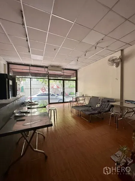 Shophouse for rent in Sathon, Bangkok - Ground-floor retail area with full-height glass shopfront, wood-look flooring, and seating.