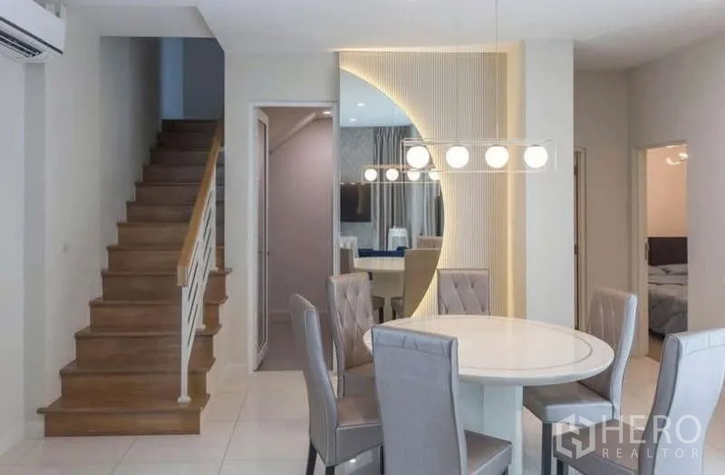 独立式住宅 出租或出售在Lat Phrao, Bangkok - 餐区带造型吊灯，旁接楼梯与镜面装饰墙。