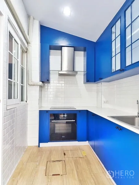联排别墅 出租或出售在Phra Pradaeng, Samut Prakan - 现代紧凑厨房，蓝色橱柜、白色地铁砖与嵌入式烤箱。
