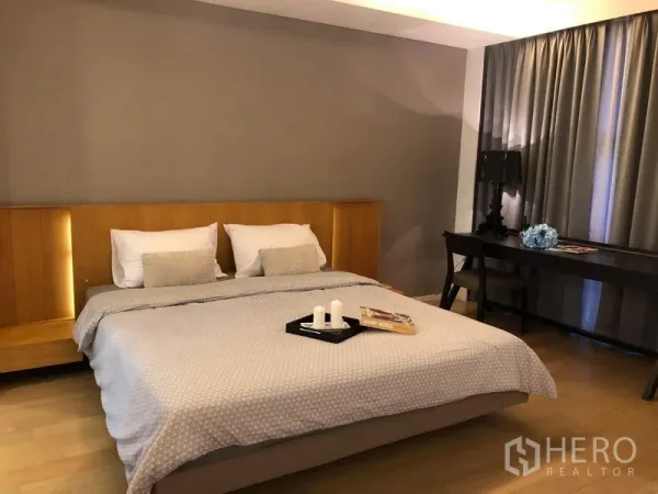 Condominium for rent in Watthana, Bangkok - Cozy bedroom with king bed, wooden headboard, desk and floor-to-ceiling curtains.