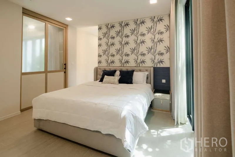 Detached House for rent in Saphan Sung, Bangkok - Cozy bedroom with patterned feature wall and sliding glass doors.