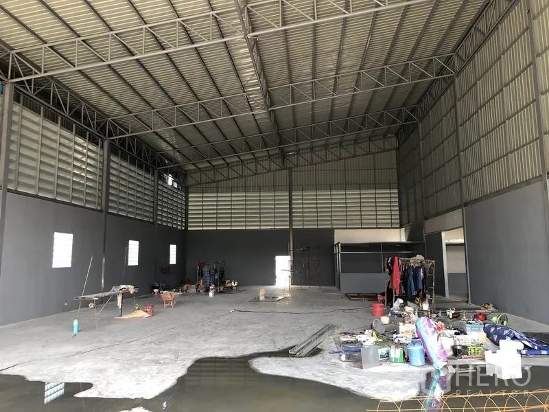 Warehouse for rent in Bang Khen, Nonthaburi - Spacious warehouse interior with high steel truss roof, concrete floor and a small office pod.