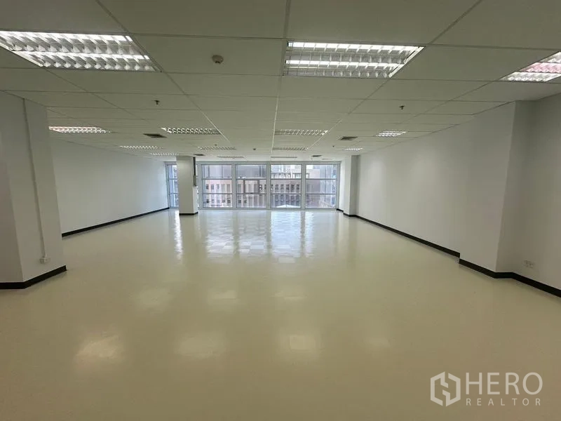 办公空间 出租在Bang Na, Bangkok - 朝向整面玻璃幕墙的开放工作区，可见城市天际线。