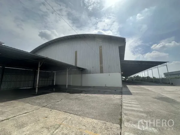 货栈 出租在Bang Pa-in, Phra Nakhon Si Ayutthaya - 仓库侧立面，带超长雨棚式装卸区与宽敞车道。
