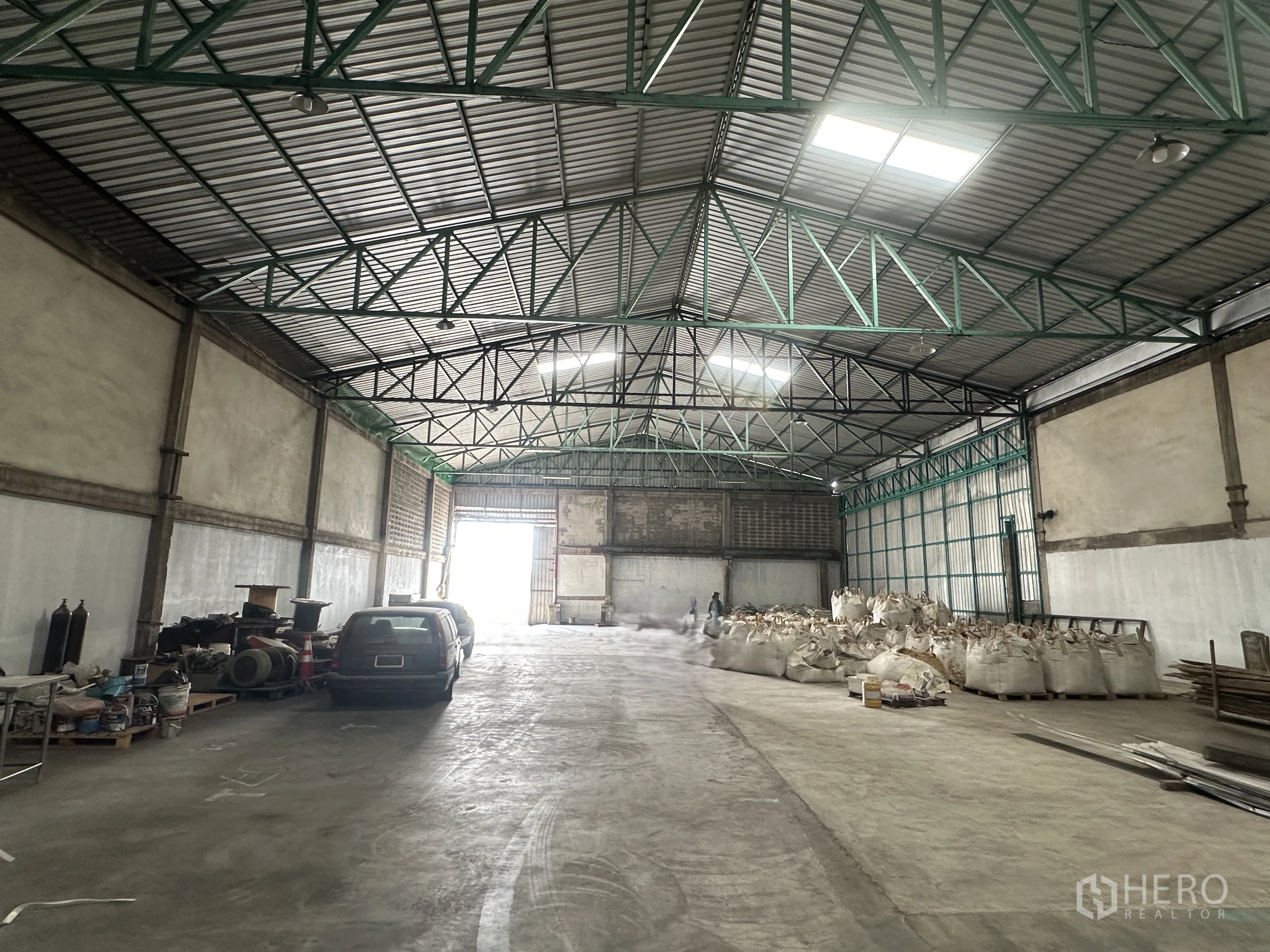 คลังสินค้า for rent in Mueang Pathum Thani, Pathum Thani - โถงโกดังสว่าง มองไปยังประตูบานเลื่อนขนาดใหญ่ มีสกายไลท์และหลังคาเมทัลชีทระบายอากาศ