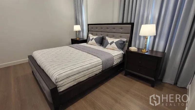 Detached House for rent or sale in Saphan Sung, Bangkok - Secondary bedroom with dark wood bedframe, twin nightstands and warm floors.