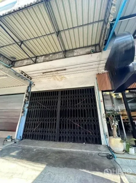 店屋 出售在Suan Luang, Bangkok - 临街店屋外立面，黑色折叠铁门与金属雨棚，靠近BTS On Nut。