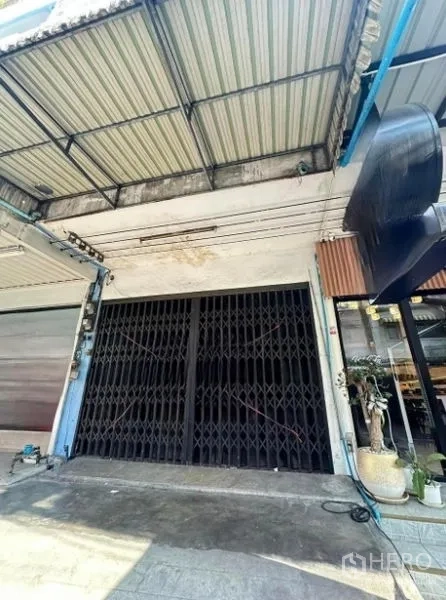 店屋 出售在Suan Luang, Bangkok - 临街店屋外立面，黑色折叠铁门与金属雨棚，靠近BTS On Nut。