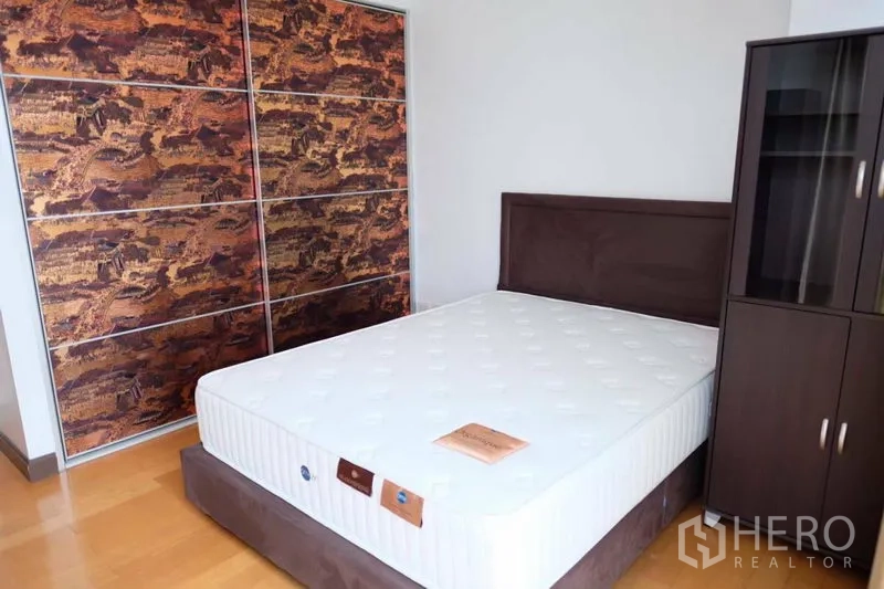 Condominium for rent in Watthana, Bangkok - Cozy bedroom with double bed, wood floors and a sliding-door wardrobe.