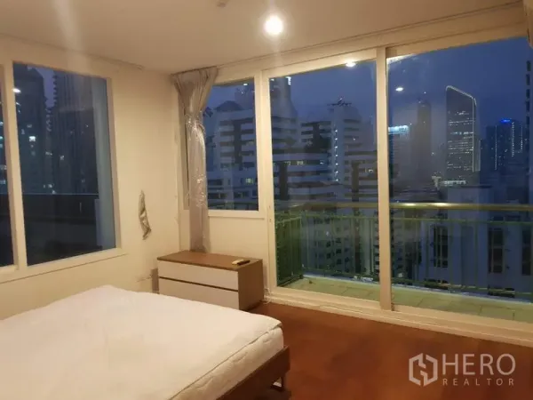Condominium for rent in Watthana, Bangkok - Master bedroom with floor-to-ceiling windows, balcony access, wood floors, and panoramic night skyline views.