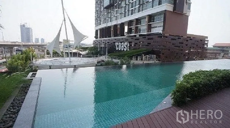 公寓 出售在Bang Na, Bangkok - 公寓无边际泳池与池畔平台，映衬城市天际线。