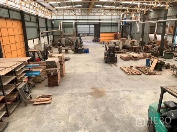 Home Office for rent in Lam Luk Ka, Pathum Thani - Expansive high-ceiling warehouse floor with machinery and stacked materials.