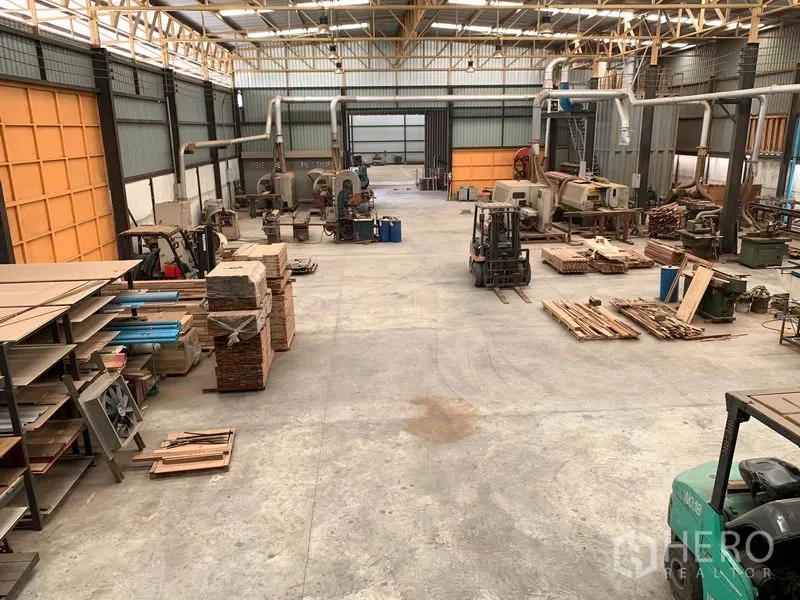 Home Office for rent in Lam Luk Ka, Pathum Thani - Expansive high-ceiling warehouse floor with machinery and stacked materials.