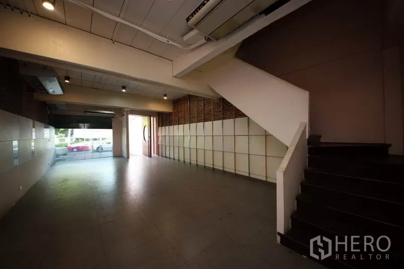 สำนักงานที่บ้าน ให้เช่าหรือขายในHuai Khwang, Bangkok - ชั้นล่างแบบโอเพ่นสเปซ มีบันได ไฟสปอตไลต์ และกระจกบานใหญ่ด้านหน้า