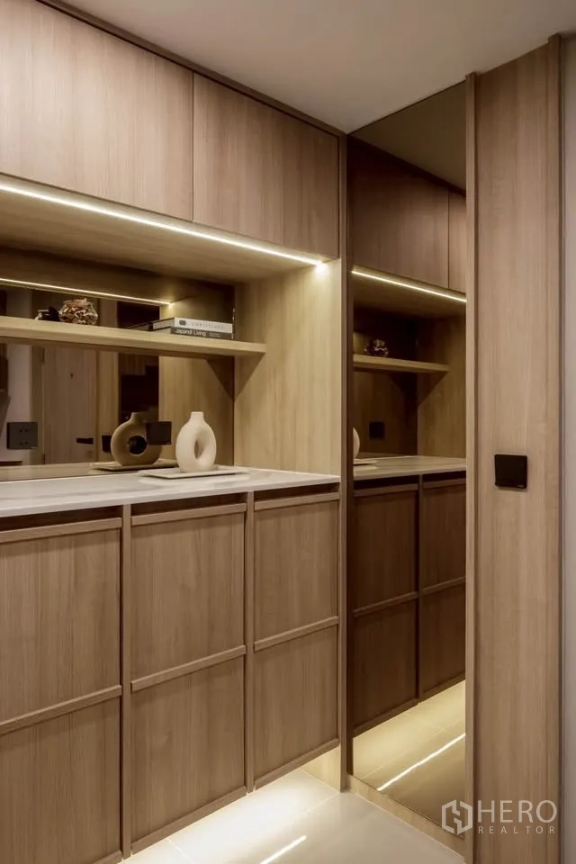 Condominium for rent in Khlong Toei, Bangkok - Entry hall with built-in wood cabinets, mirror, and under-cabinet lighting.
