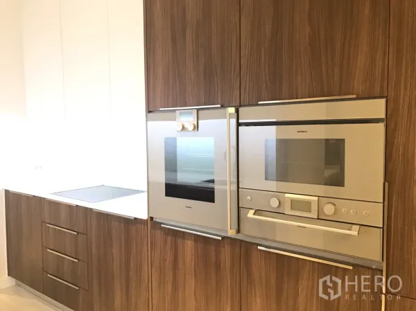 คอนโด ให้เช่าในPathum Wan, Bangkok - ครัวสมัยใหม่พร้อมตู้ลายไม้ เตาอบ ไมโครเวฟ และเตาอินดักชัน