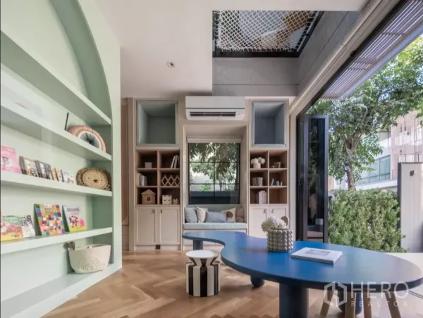 บ้าน ให้เช่าหรือขายในPhra Khanong, Bangkok - ห้องอเนกประสงค์สว่างพร้อมชั้นบิวต์อินสีเขียว โต๊ะสีน้ำเงิน และวิวสวน