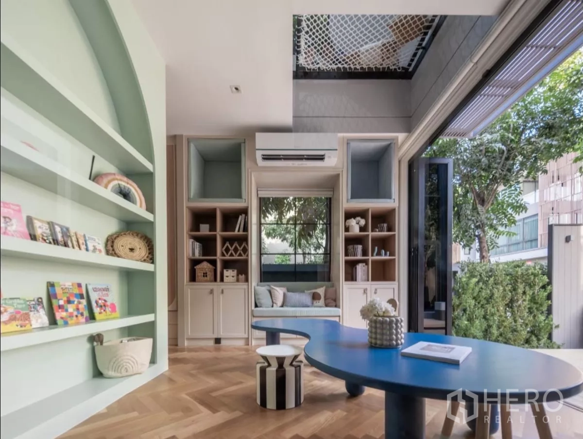 บ้าน ให้เช่าหรือขายในPhra Khanong, Bangkok - ห้องอเนกประสงค์สว่างพร้อมชั้นบิวต์อินสีเขียว โต๊ะสีน้ำเงิน และวิวสวน