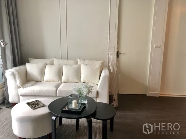 คอนโด ให้เช่าในPathum Wan, Bangkok - ห้องนั่งเล่นอบอุ่น โซฟาสีครีม โต๊ะกลางซ้อน และพื้นไม้