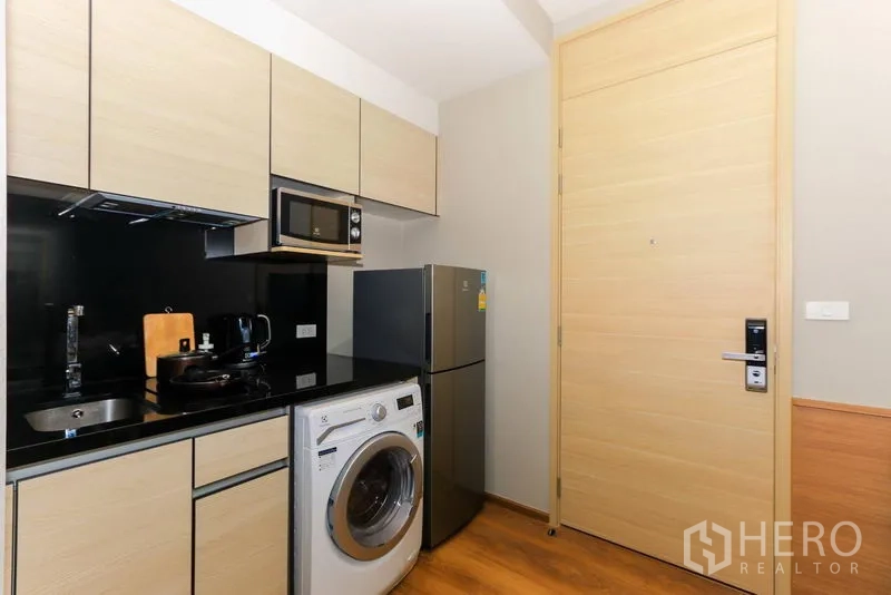 คอนโด ให้เช่าในKhlong Toei, Bangkok - ครัวบิลต์อินสมัยใหม่ ผนังกันเปื้อนสีดำ พร้อมไมโครเวฟ ตู้เย็น และเครื่องซักผ้า
