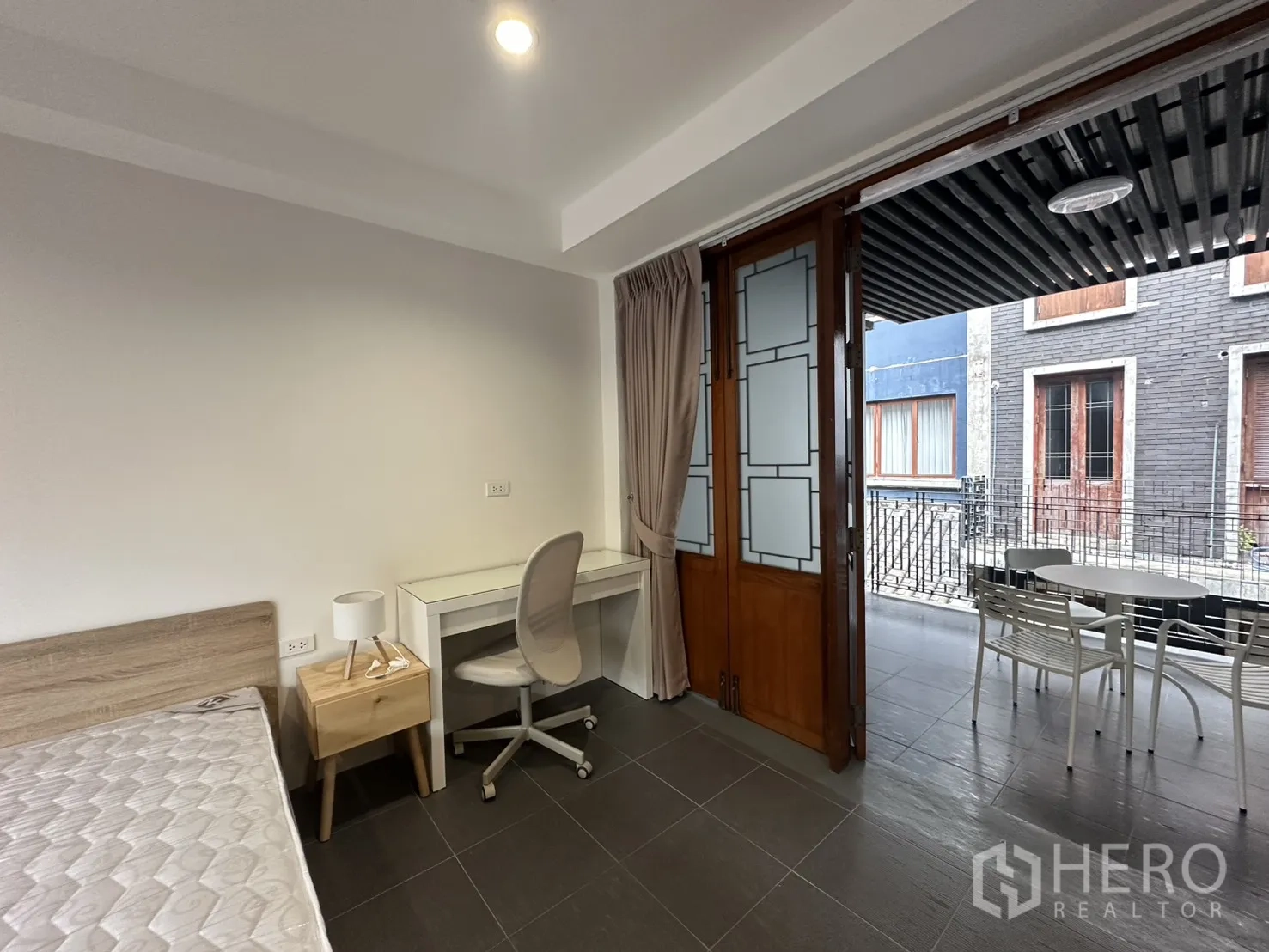 Apartment for rent in Pathum Wan, Bangkok - Sheltered terrace with small round table and white chairs overlooking inner façades.