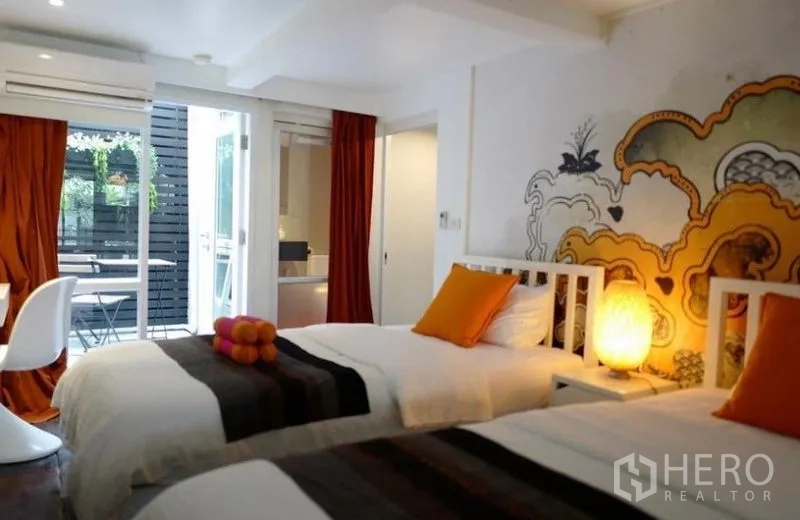 ทาวน์เฮาส์ ให้เช่าในKhlong Toei, Bangkok - ห้องนอนเตียงคู่เปิดออกสู่เทอเรซเล็ก ผนังลายศิลป์ หมอนสีส้ม