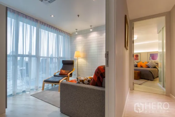 公寓 出租在Pathum Wan, Bangkok - 窗边阅读角，落地窗观城景，躺椅、落地灯与小沙发。