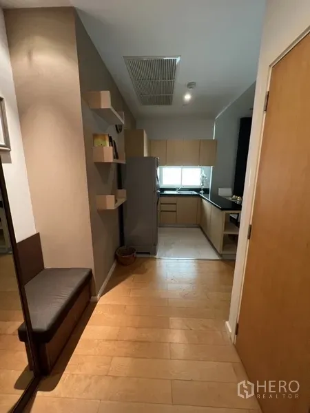 公寓 出租在Chatuchak, Bangkok - 入口走廊设壁架，通向带窗的L形厨房与浅木色橱柜。