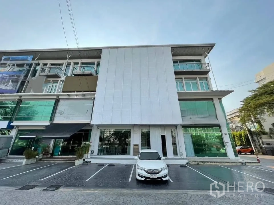 店屋 for sale in Prawet, Bangkok - 多层店屋外立面，整面玻璃与前方停车位。