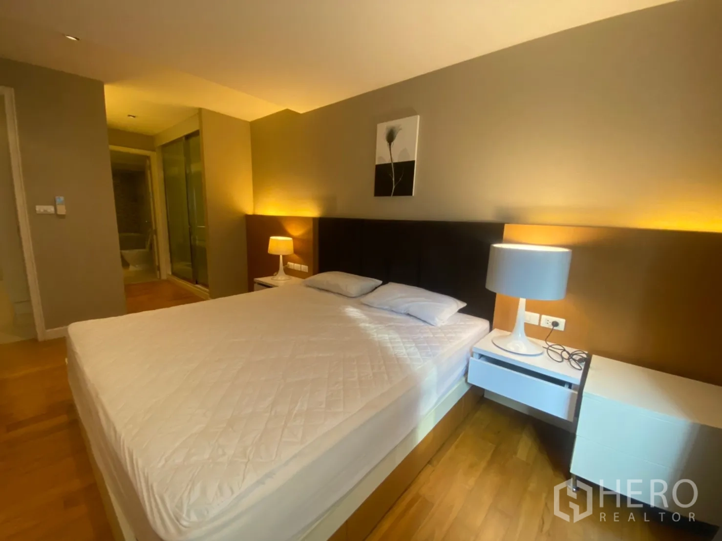 公寓 出租在Watthana, Bangkok - 主卧灯光温暖，设床头灯，可见套内卫浴入口。