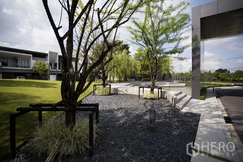 联排别墅 出租在Samut Prakan - 景观化公共花园，树木、卵石步道与座椅。