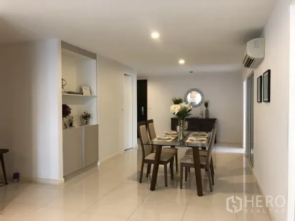 Condominium for rent in Watthana, Bangkok - Open-plan dining area with a glass-top table set for six, built-in shelving, glossy tile floors, and ceiling lights.